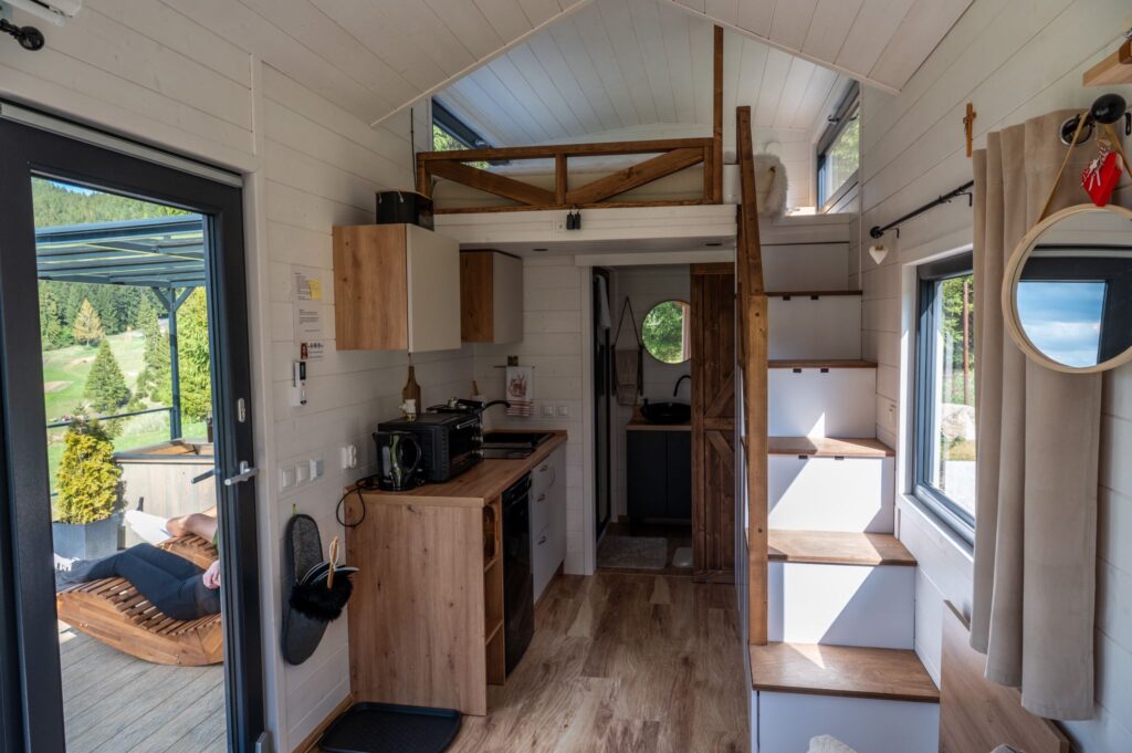 Küchenzeile und Treppe zum Zwischengeschoss in einem Tiny House mit Eckfenster