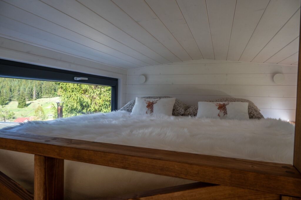 Schlafzimmer im Zwischengeschoss eines Tiny House mit Eckfenster