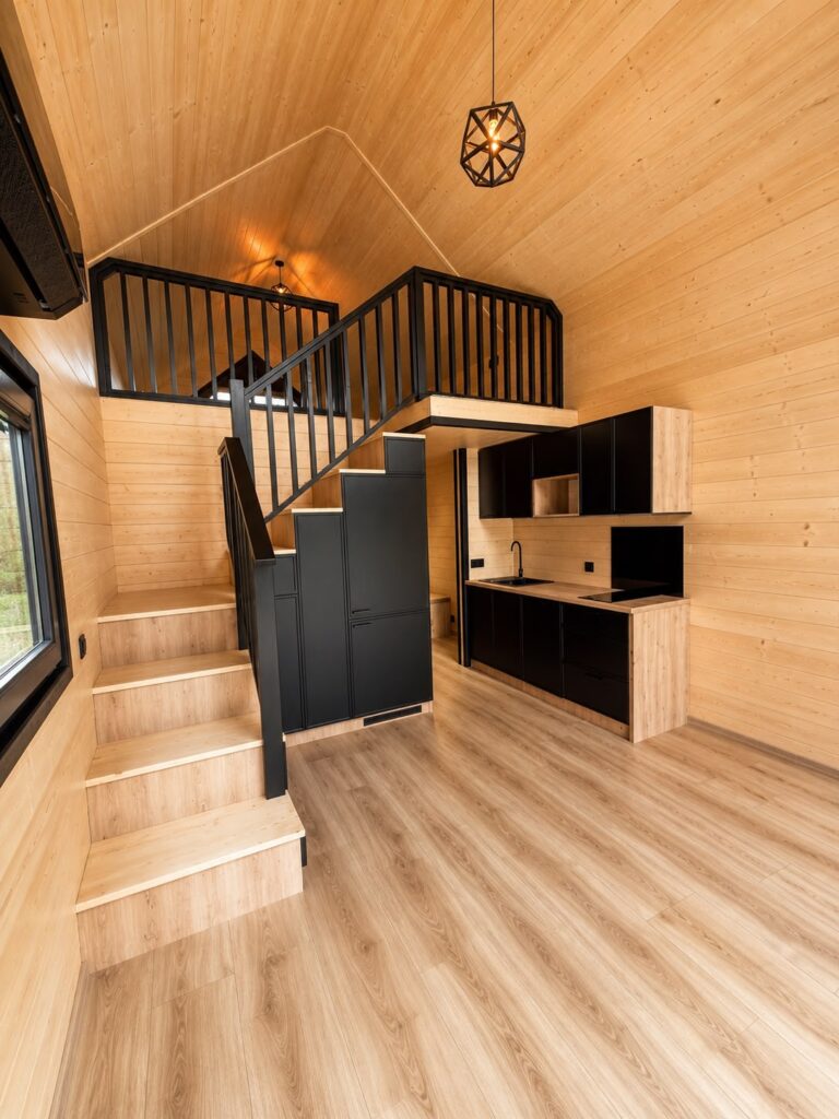 Treppe zur Galerie mit Schränken, im Hintergrund die Küchenzeile und der Flur im Modulhaus Modular 2